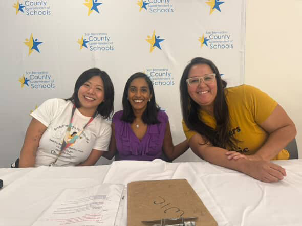 Melody with fellow panelists at a community event table.